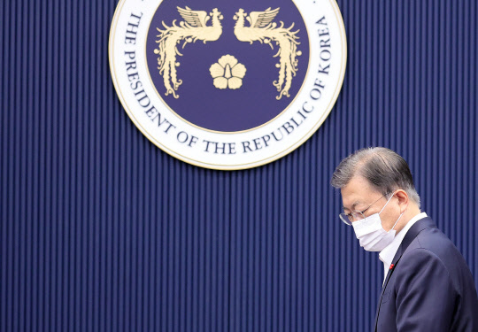 21일 문재인 대통령이 청와대 여민관에서 열린 영상국무회의에서 국기에 경례를 마친 뒤 자리에 앉고 있다. 연합뉴스,